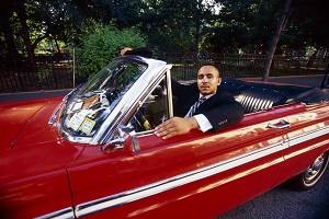 man sitting in red classic car